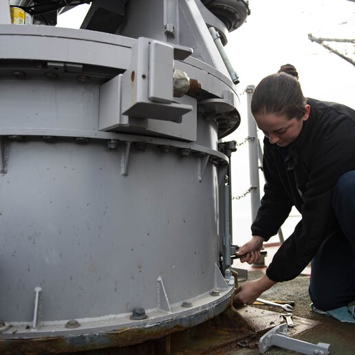 Tightening bolts at the base of a MK-18 mount aboard a guided-missle cruiser.
