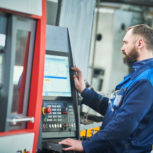 Machine operator standing at control panel.