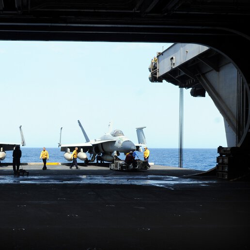 F-14 tomcat on deck and being loaded into aircraft elevator.
