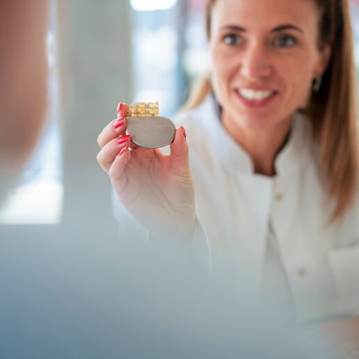 Woman in lab coat holding a pacemaker