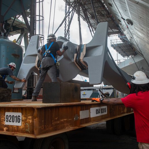 Shipbuilding workers prepare to attach the starboard anchor of the Nimitz-class aircraft carrier (CVN 74).