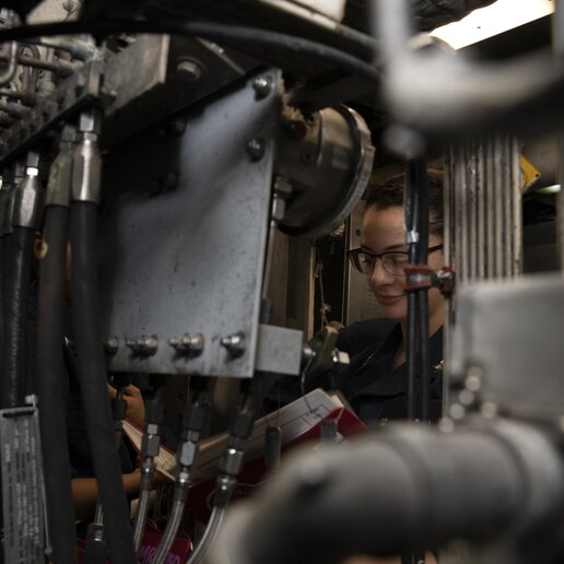 Electrician’s Mate on the submarine tender USS Emory S. Land (AS 39) reviews an Engineering Operational Sequencing System book in the engine room.