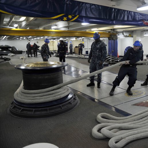 Sailors aboard a CVN 75 secure a line to the capstan while hoisting the anchor chain aboard the ship. 