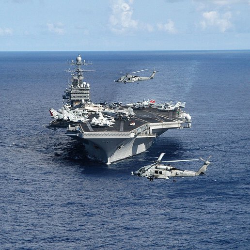 A Navy SH-60 Seahawk helicopter flying over the bow of the aircraft carrier USS Theodore Roosevelt (CVN 71).