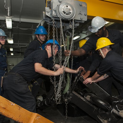 SS Carl Vinson (CVN 70) deck department sailors securing an anchor using a bridge crane.
