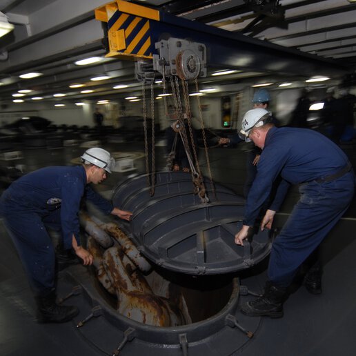 Sailors removing the anchor chain cover above the starboard side haws pipe.