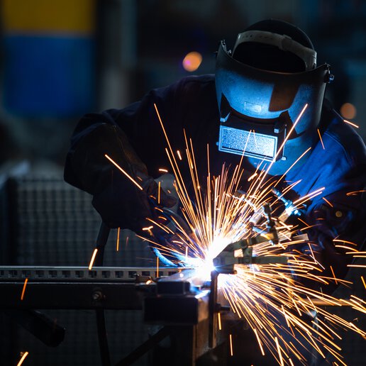 Workers wearing industrial uniforms and Welded Iron Mask at Steel welding plants, industrial safety first concept.