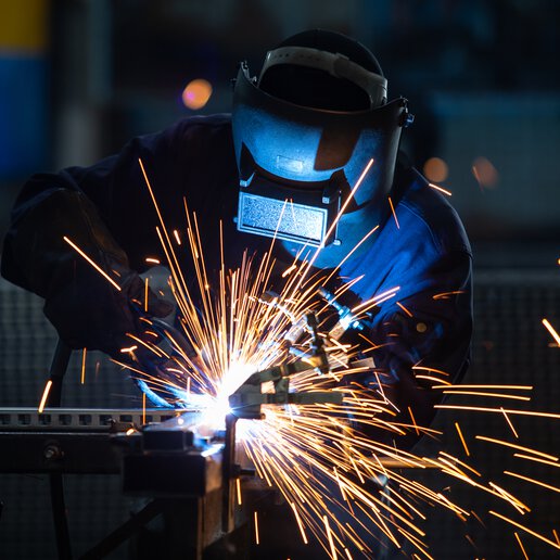 Welder welding with welding helmet and appropriate gear.
